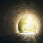 暗いトンネルの先に明るい光が差し込む希望を感じる風景