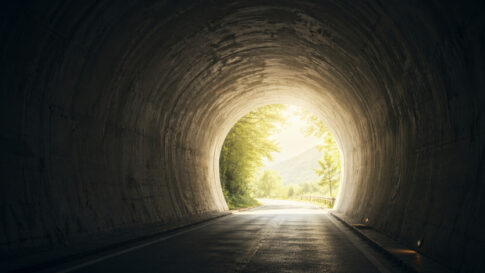 暗いトンネルの先に明るい光が差し込む希望を感じる風景