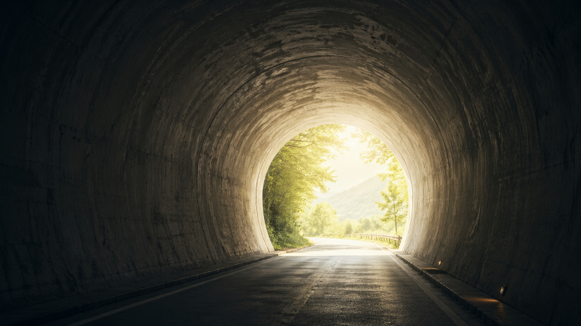 暗いトンネルの先に明るい光が差し込む希望を感じる風景